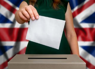 An anonymous woman posts her voting form into a UK ballot box