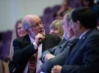 Roland Clift holding a microphone sat with crowd during lecture