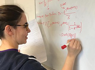 A student writing an equation on a white board