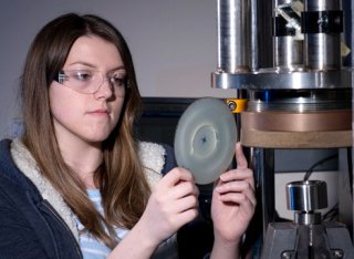 Female student using mechanical engineering equipment