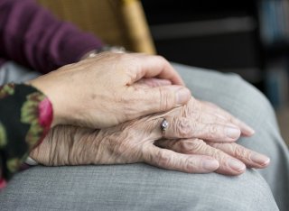 Carer holding hand of an elderly woman