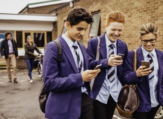 Three school boys walk and text at school
