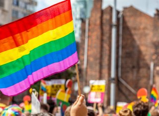 An LGBTIQ flag is waved in a crowd of people