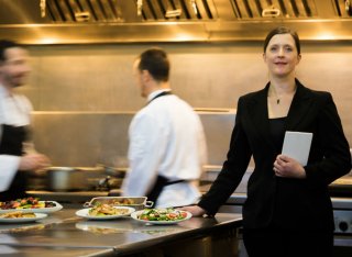 A restaurant manager stands in a busy hotel restaurant kitchen