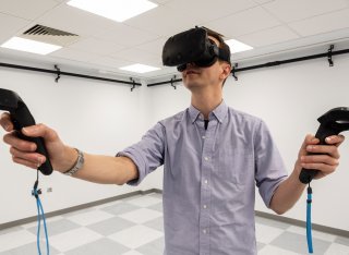 Man wearing a virtual reality headset and holding virtual reality controllers