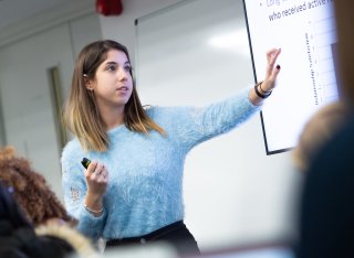 Female student giving presentation in front of whiteboard