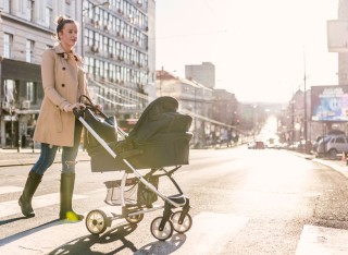 Mother pushing her baby in a pram across a road