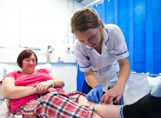 Female nursing student applying dressing to a leg wound