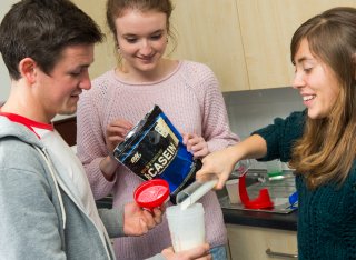 Students pouring casein into a beaker