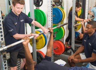 Students spotting each other using weights