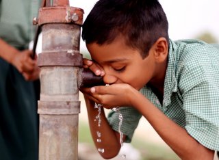 Boy drinking water from a pump