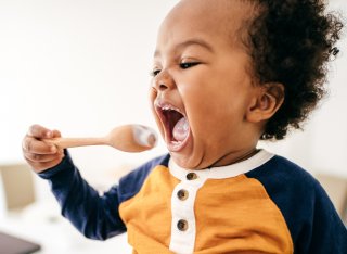 Toddler eating yoghurt off a spoon