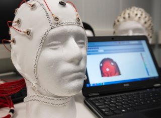 A Styrofoam head with electrodes attached next to a laptop