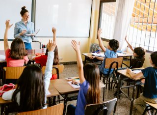 School children with their hands up in classroom
