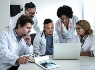 Group of doctors gathered around a laptop