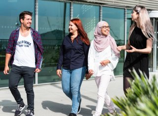 Four students walking alongside each other