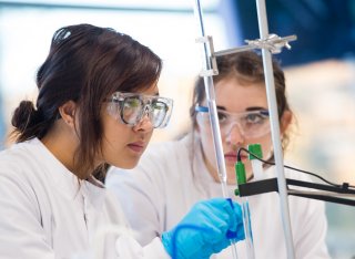 Two students using titration equipment in a lab