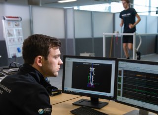 Student running on a treadmill while another student monitors his performance on a PC