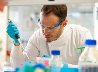 Student in a lab coat using a pipette