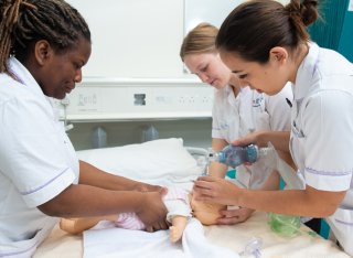 Midwifery students practising CPR on a baby mannequin