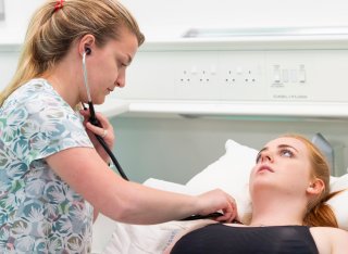 Student checking chest of patient using stethoscope