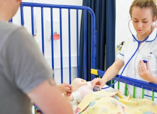 Student nurse checking heartbeat of child mannequin