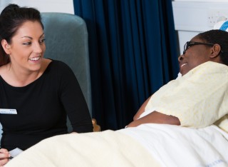 Mental health nursing student speaking to patient in a hospital bed
