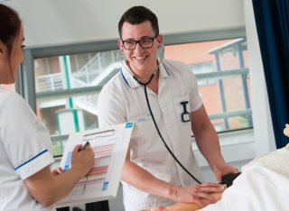 Student nurse checking breathing on adult mannequin