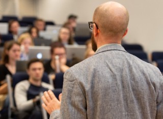 Lecturer speaks to students a busy lecture hall