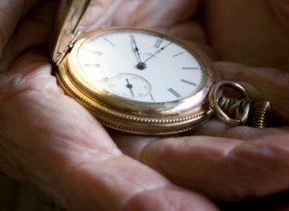 Pocket watch held in an old persons hands