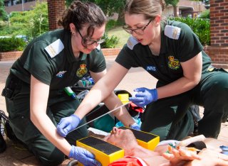Two trainee paramedics providing medical care to patient strapped to a board