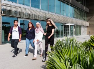 Group of postgraduate students walking through campus together