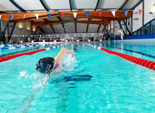 Swimmer doing front crawl in the Olympic-sized pool at Surrey Sports Park