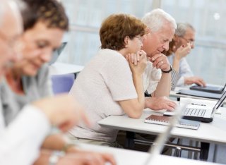 A group of elderly people take part in a computer class