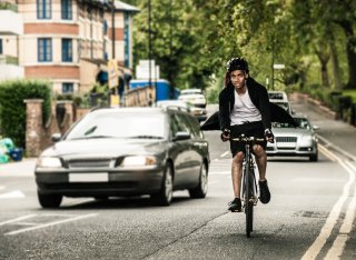 A cyclist on an urban road is overtaken by a car