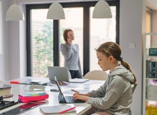 Girl studying at home in the kitchen whilst mum works from home