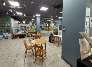 Chairs, tables and displays in a lit room, which is ZERO. On a vertical wall a small air quality monitor can be seen