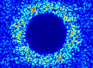 A blue circle with lighter blue pattern around it which shows light scattering from a thin silicon membrane