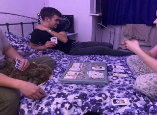 Surrey student Corinne with friends playing cards on a bed