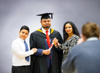 A graduand having their photo taken with their family