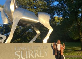 Student Rachael standing by Surrey University deer statue