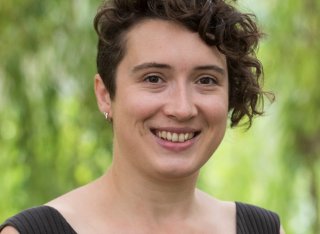 Photo of Dr Emily McDougal smiling from the shoulders up with blurred trees in the background.