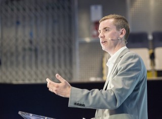 Dr Gardner stands on a podium addressing an audience