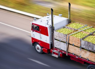 A lorry drives large crates of apples along a road