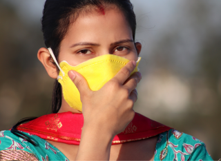 A woman clutches her mask to her face during pollution in Delhi