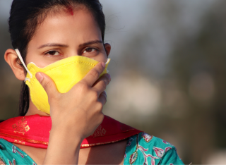 A woman clutches her mask to her face during pollution in Delhi