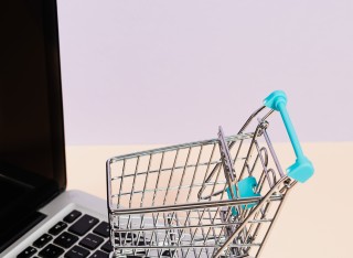 Miniature shopping trolley resting on laptop keyboard