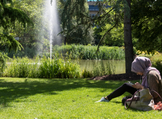 Woman sits beside the fountain at the university's grounds