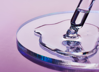 Stock image of a pipette injecting a clear substance onto a petri dish. 