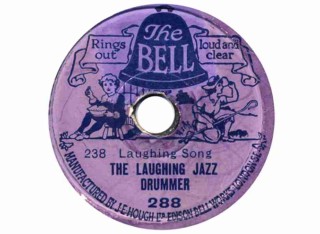 Purple record with black font: The Bell Rings out Loud and Clear. Laughing Song. The Laughing Jazz Drummer